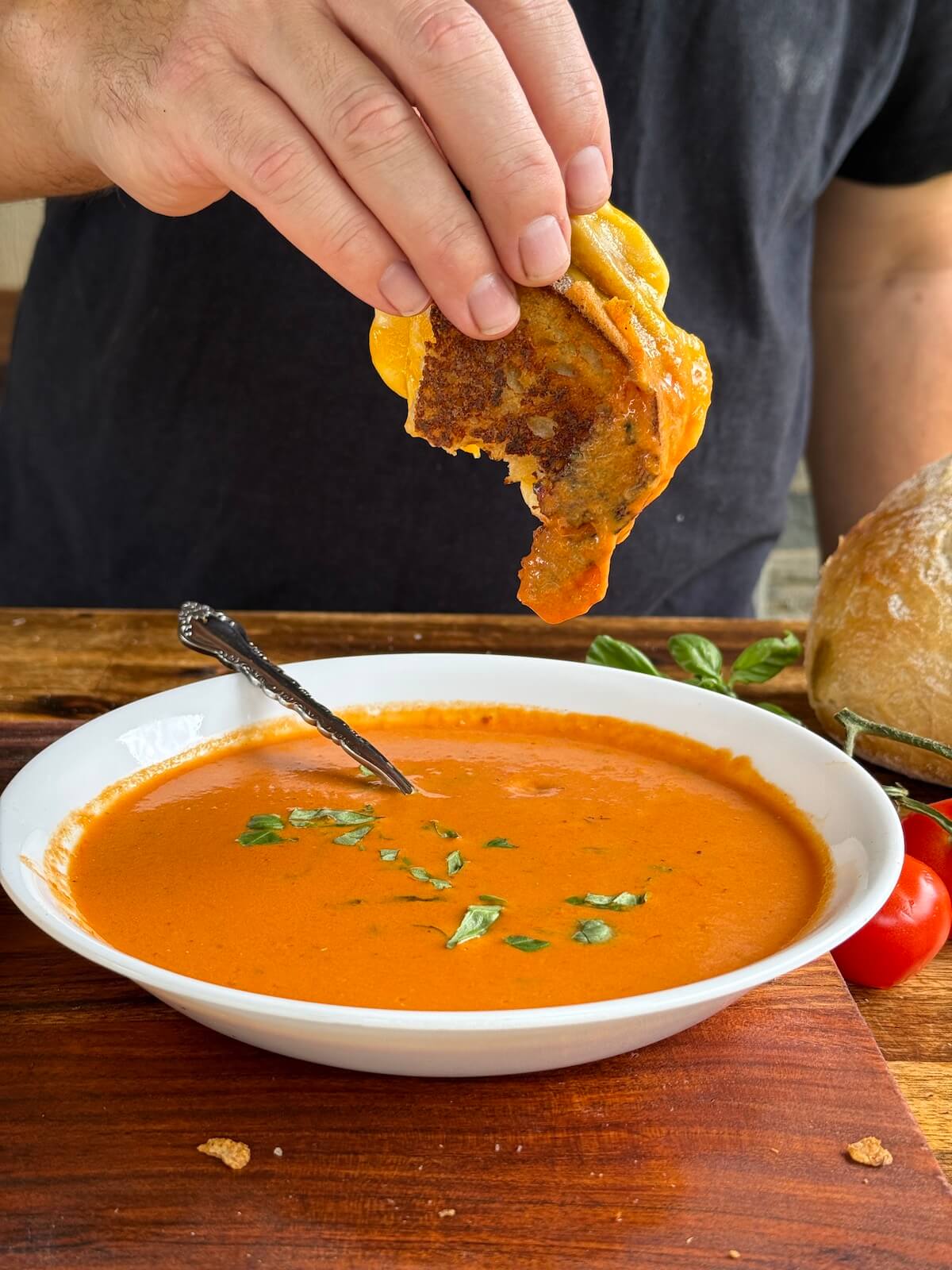 dipping a grilled cheese sandwich into a bowl of tomato soup