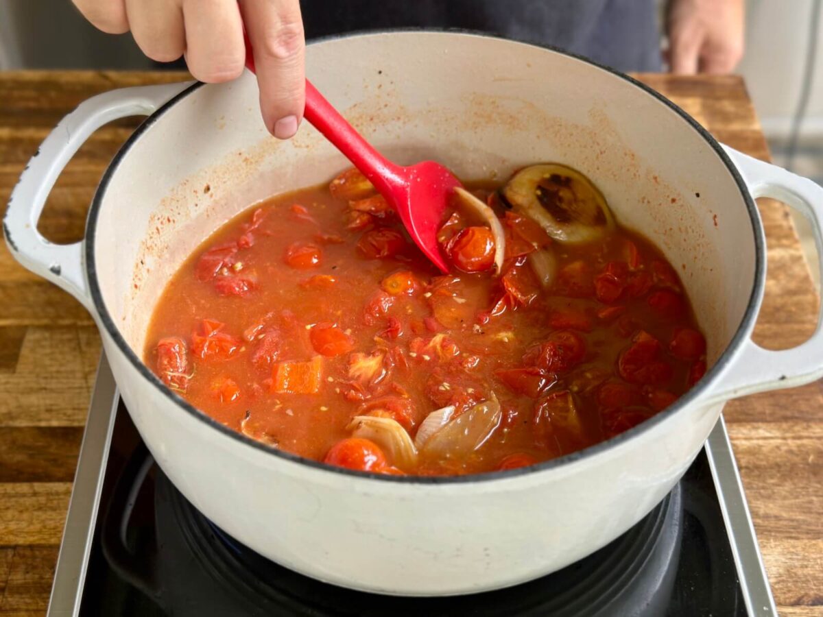 stirring roasted tomatoes, onions, and chicken stock in a Dutch oven