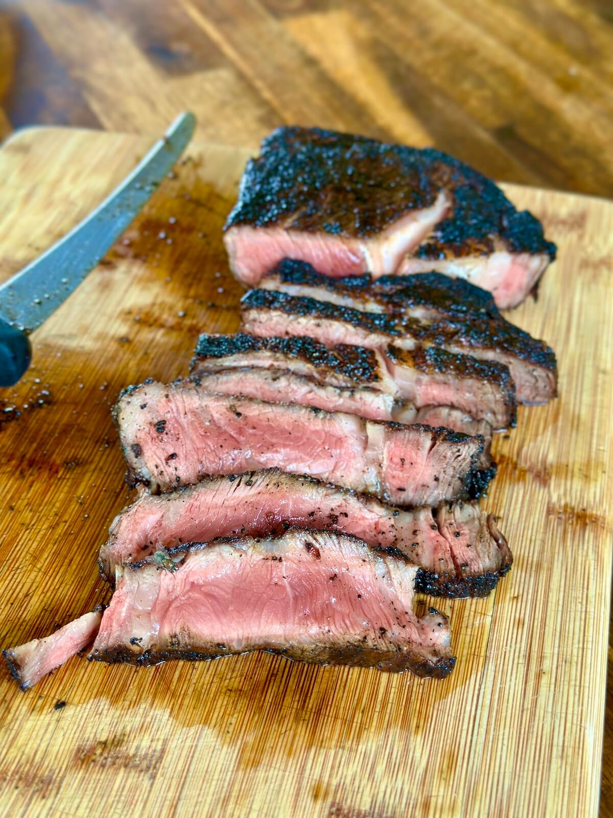 black and blue style Pittsburgh ribeye steak with a charred crust sliced on a cutting board