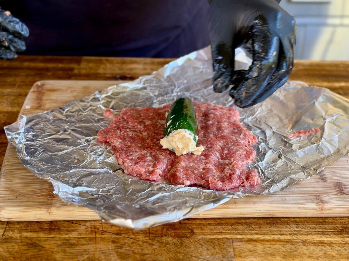 flattened portion of ground pork sausage with a cheese-stuffed jalalpeno pepper on top