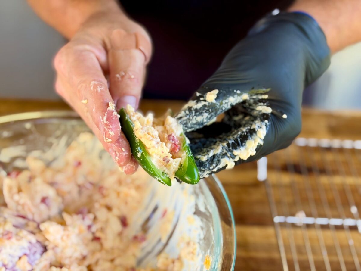 stuffing a raw jalapeno pepper with homemade pimento cheese mixture